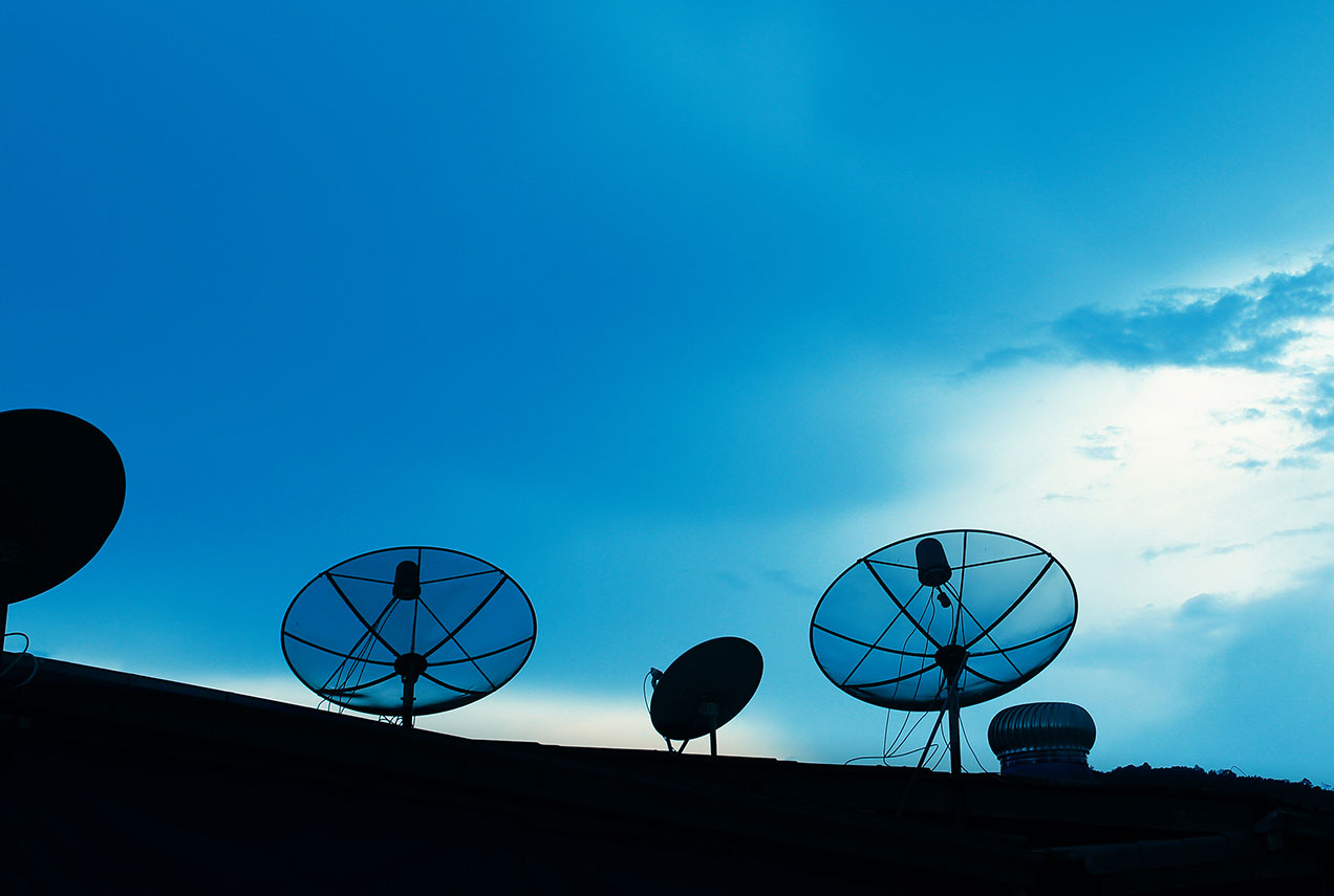A satellite dish mounted on a roof against a clear sky, illustrating a typical satellite internet installation.