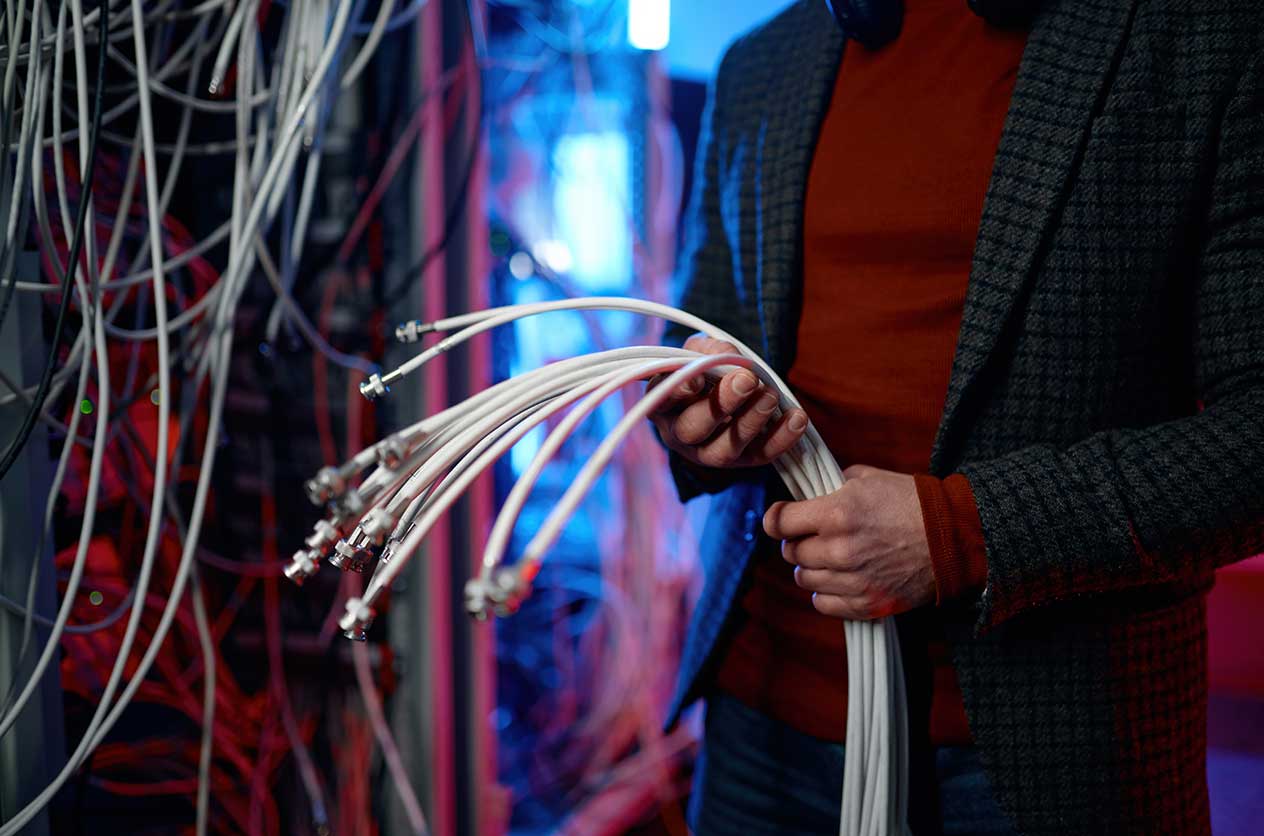 Closeup view of a technician with fibre cables in hand while working in a fibre to the room installation.